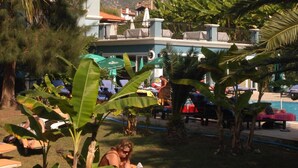 A resort with outdoor lounge chairs, palm trees, and a view of mountains in the background. - Antas Deluxe Apartments (Fethiye)