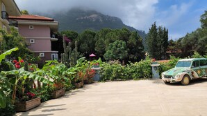A vintage car parked in a garden with a mountain in the background. - Antas Deluxe Apartments (Fethiye)