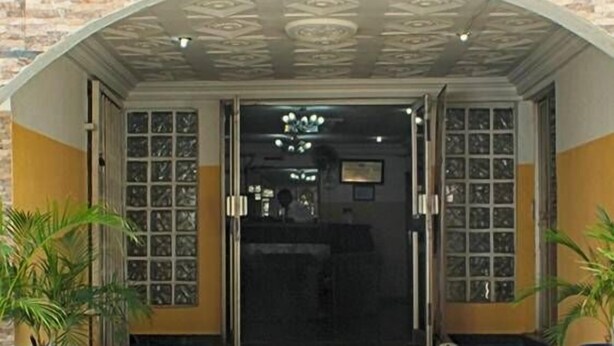 A hotel entrance with a stone facade, a glass door, and a ceiling with a geometric pattern. - Yaban Hotel (Abuja)