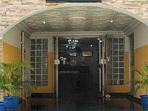 A hotel entrance with a stone facade, a glass door, and a ceiling with a geometric pattern. - Yaban Hotel (Abuja)