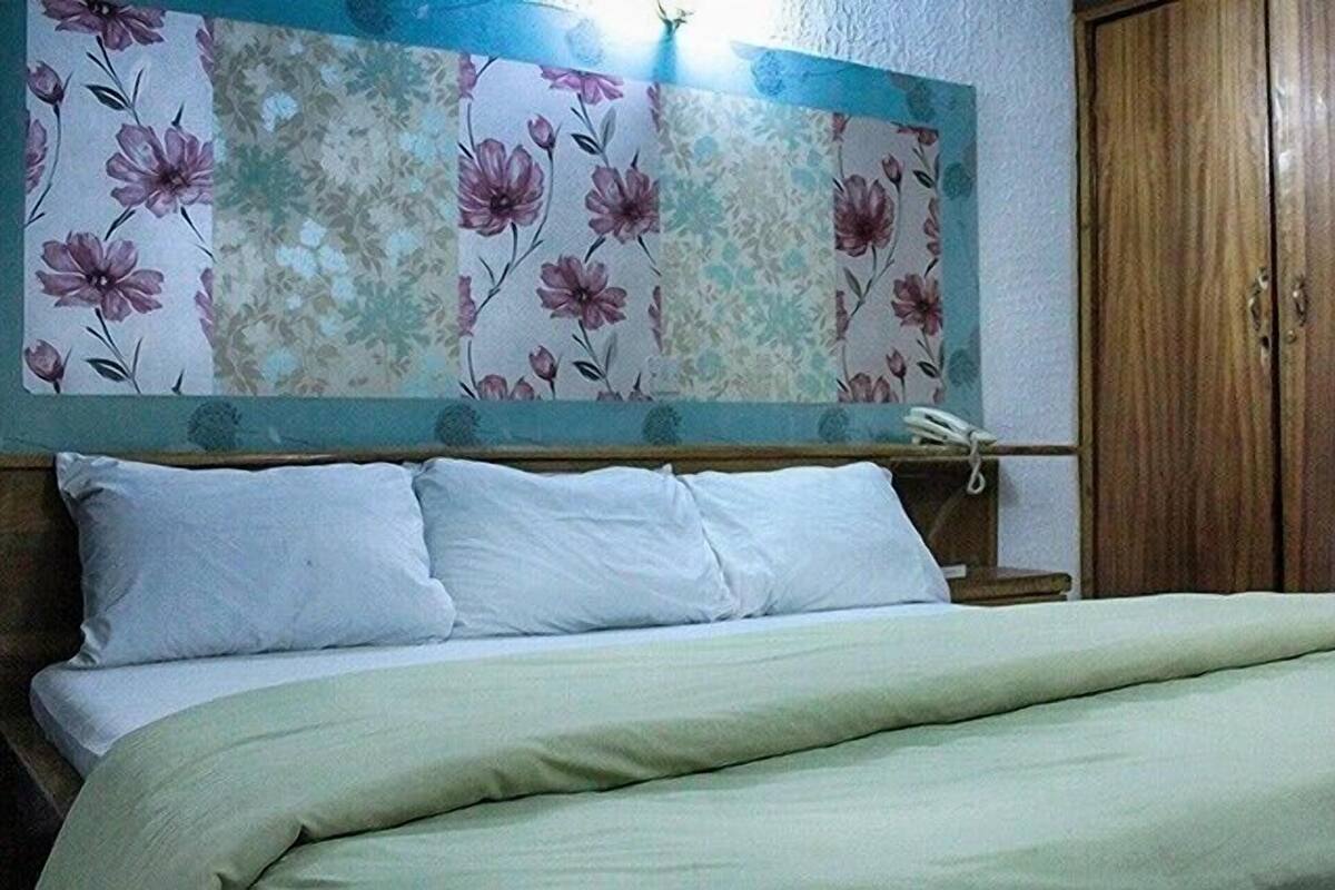 Un dormitorio con una cama, un armario de madera y una pared con estampado floral.