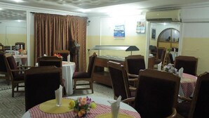 A dining area with round tables, chairs, and a decorative centerpiece. - Yaban Hotel (Abuja)
