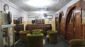 A lobby with a reception desk, green armchairs, a clock, and a mirror. - Yaban Hotel (Abuja)