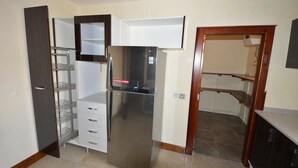 A compact kitchen with a stainless steel refrigerator, a built-in microwave, and a wooden cabinet. - Sharon Ultimate Hotels (Abuja)