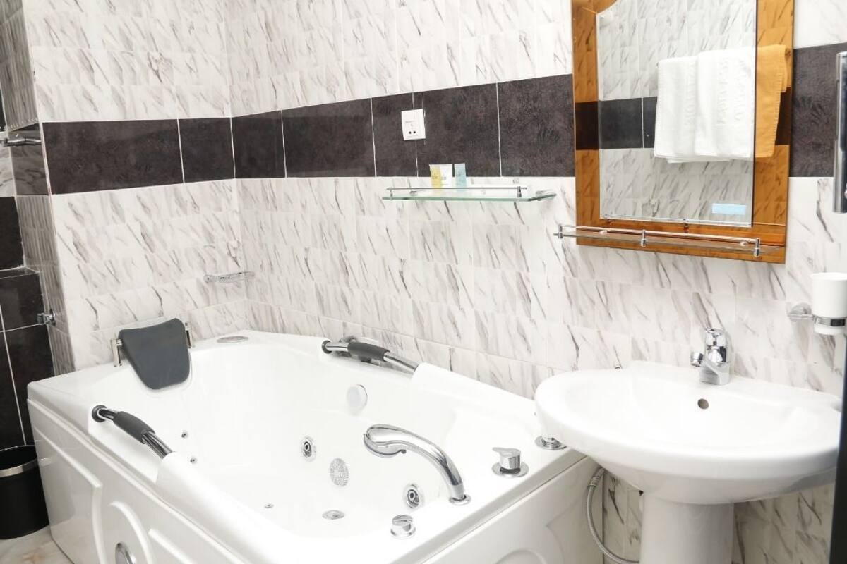 A modern bathroom with a white bathtub, a sink, and a mirror.