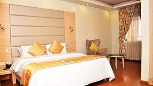 A hotel room with a large bed, a small round table, and a chair. - Sharon Ultimate Hotels (Abuja)