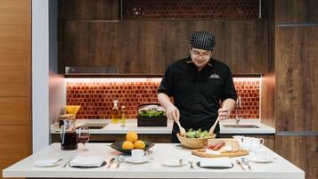 A chef preparing food in a modern kitchen with wooden cabinets and a brick backsplash.