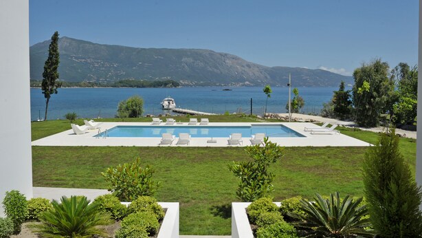 A pool with lounge chairs, a view of the sea, and mountains in the background. - K&K Luxury Beach Villas (Corfu)