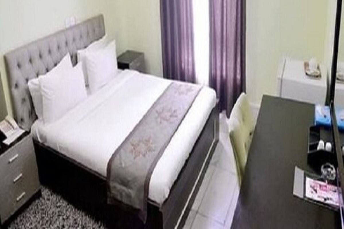 A hotel room with a bed, a desk, and a chair.
