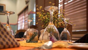 Un tavolo da pranzo con diversi vasi di vetro contenenti fiori e piante, su una tovaglia di legno.