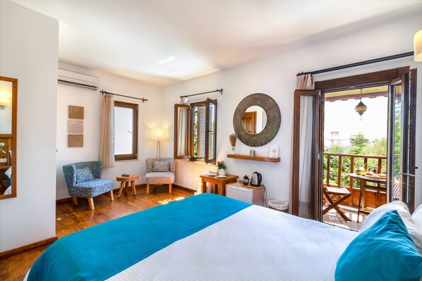 Un dormitorio con una cama grande, una silla, una mesita y un balcón con mesa y sillas.