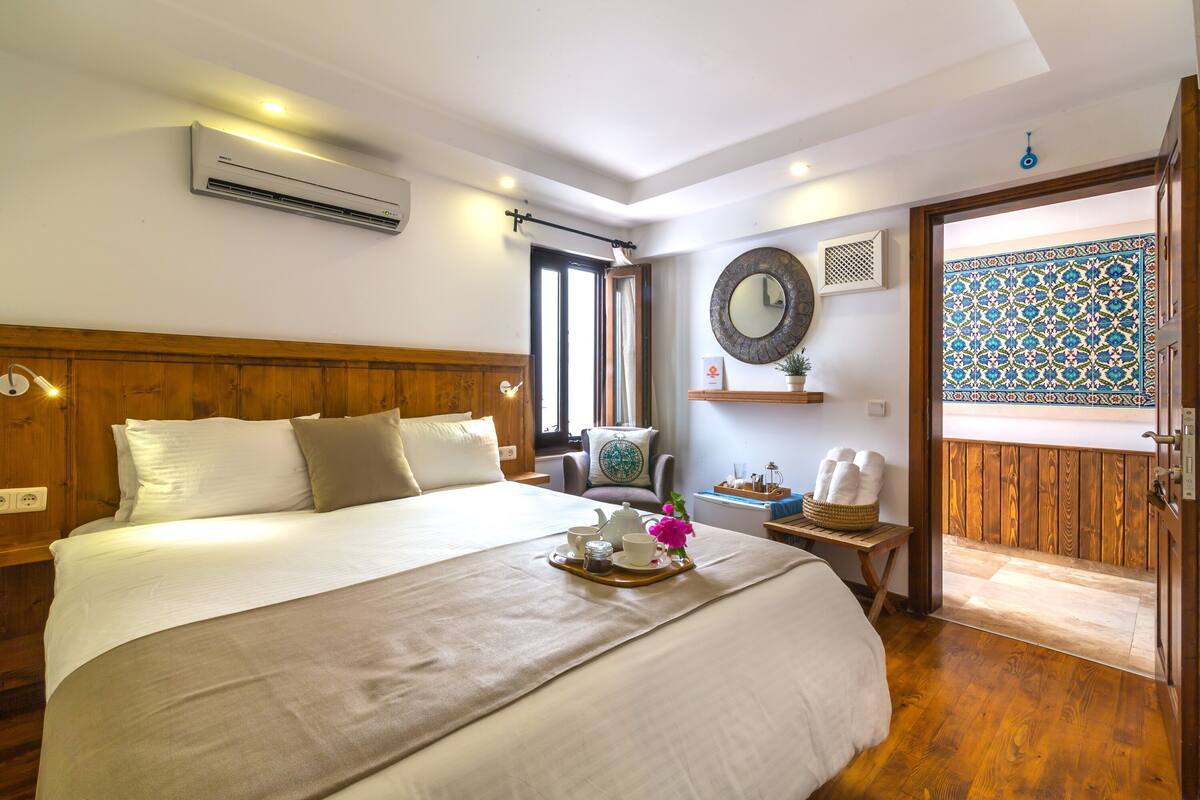 Une chambre d’hôtel équipée d’un lit, d’une table de chevet, d’un appareil de climatisation, d’une fenêtre et offrant une vue sur l’extérieur.