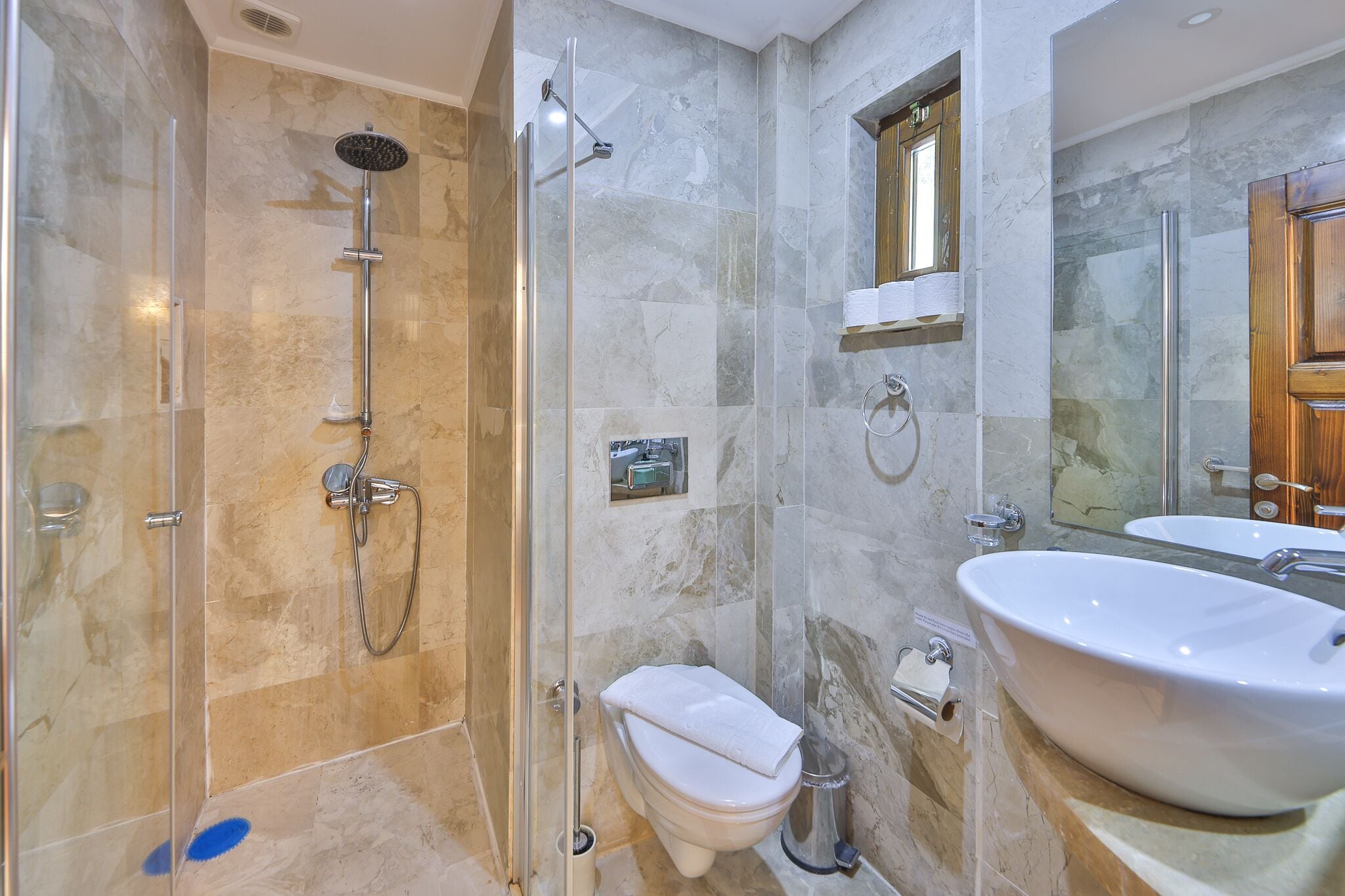A modern bathroom with a glass-enclosed shower, a white toilet, and a large white sink.
