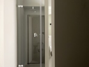 A glass door leading to a shower area with a control panel and a towel rack. - Hotel Mons Am Goetheplatz (Munich)