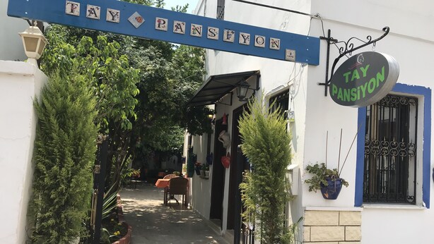 Une ruelle étroite où se trouve un café appelé « TAY PANSIYON », avec une enseigne au-dessus.