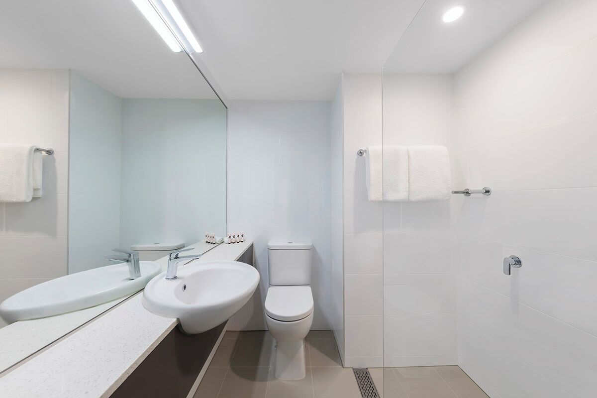 Un baño moderno con lavamanos blanco, inodoro y zona de ducha.