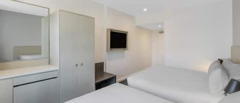 A modern hotel room with a bed, a desk, a wardrobe, and a TV.