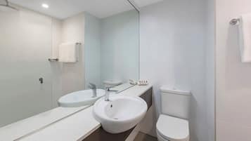 Casa de banho moderna com cabine de duche em vidro, lavatório branco e sanita.
