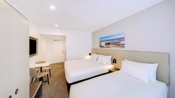 Een hotelkamer met twee bedden, een bureau en een stoel.