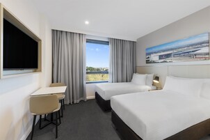 Une chambre d’hôtel avec deux lits, un bureau et une télévision.