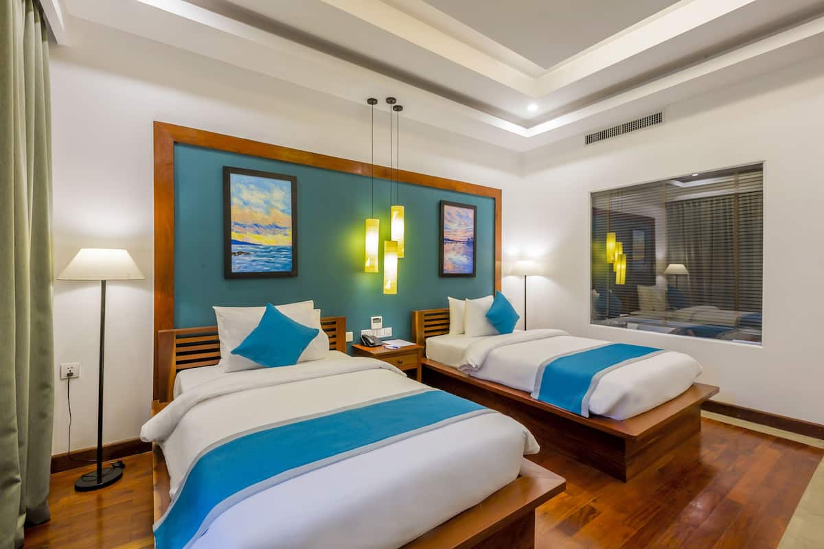 A hotel room with two beds, a large window, and a view of the city.