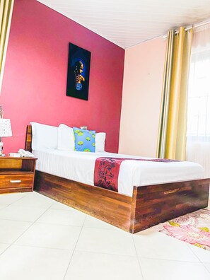 Un dormitorio con cama, mesita de noche, teléfono y un cuadro en la pared.