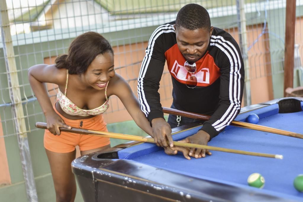 Two people playing pool at an outdoor table.