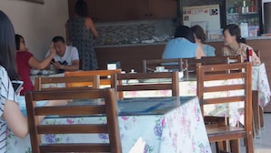 A restaurant interior with wooden chairs and tables, a tiled backsplash, and a Coca-Cola refrigerator. - Pinara Pension & Guesthouse (Fethiye)