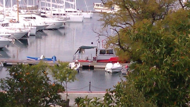 A marina with multiple boats docked, surrounded by greenery and hills in the background. - Pinara Pension & Guesthouse (Fethiye)