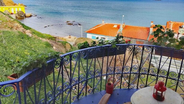 A balcony with a view of the sea, a red lantern, and a table with a chair. - Mitos Hotel (Bozcaada)
