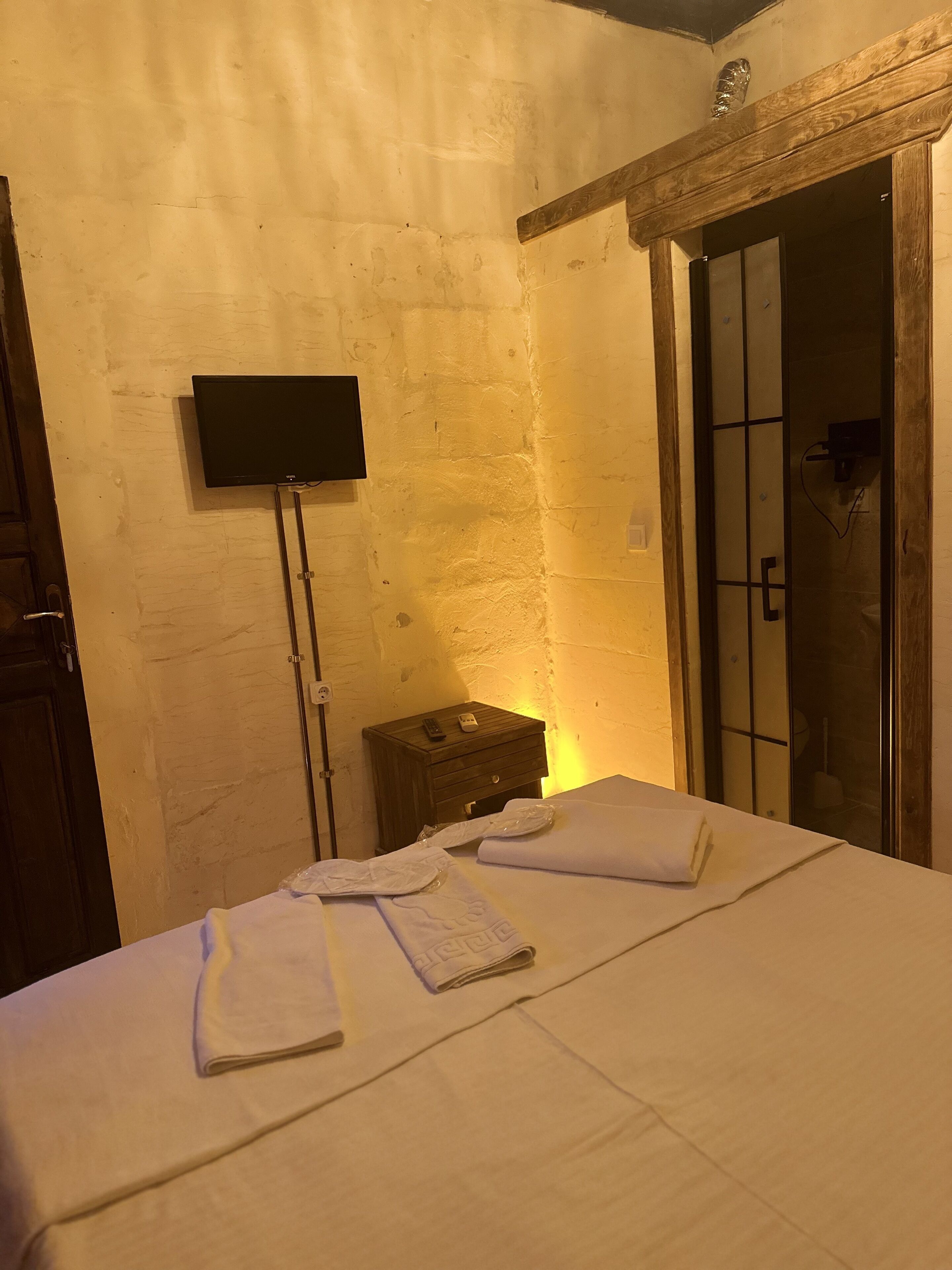 Habitación de hotel con una cama, una mesita de noche con un control remoto y un televisor montado en la pared.