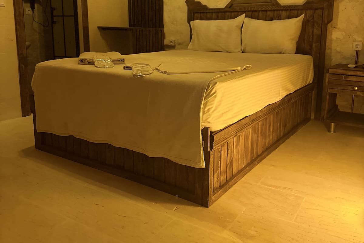 A bedroom with a wooden bed, a nightstand, and a mirror.