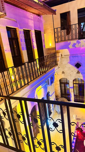 A multi-story building with balconies, a stone wall, and a fan. - Hotel Serce Konagi (Sanliurfa)