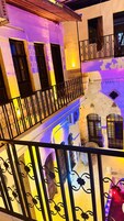 Un edificio de varios pisos con balcones, un muro de piedra y un ventilador.