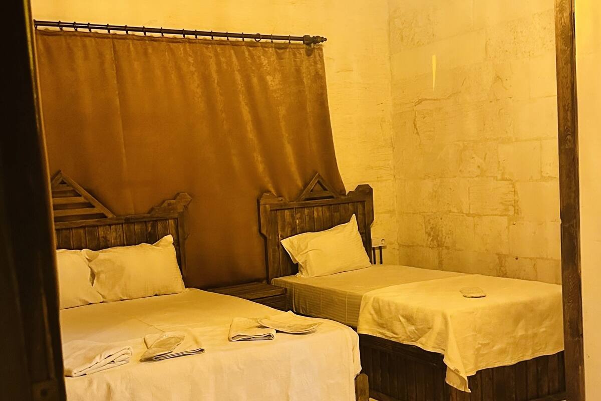 A room with two wooden beds, a wooden ceiling, and a stone wall.