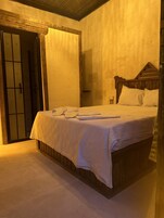 Una habitación con una cama, cabecera de madera y puerta de diseño tradicional.