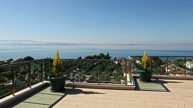 A balcony with potted plants, a clear view of the sea, and distant mountains. - Hotel Santana Life (Edremit)