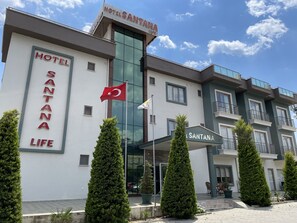A hotel named 'SANTANA LIFE' with a modern architectural design, featuring a prominent sign and a flag. - Hotel Santana Life (Edremit)