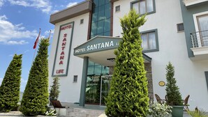 A hotel with a modern facade, a prominent sign reading "Hotel Santana Life," and a well-maintained entrance area with potted plants and outdoor seating. - Hotel Santana Life (Edremit)