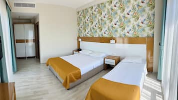 Habitación de hotel con dos camas, cabecero de madera, mesita de noche, teléfono y armario.