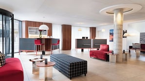 Eine moderne Hotelhalle mit Bar, Sitzbereichen und einer großen Säule.