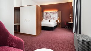 Ein Hotelzimmer mit Bett, Schreibtisch, Stuhl und Kleiderschrank.