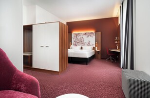 A hotel room with a bed, a desk, a chair, and a wardrobe.