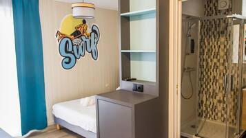 Een moderne hotelkamer met een bed, een klein bureau, een douche en een muur met een grafische afbeelding.