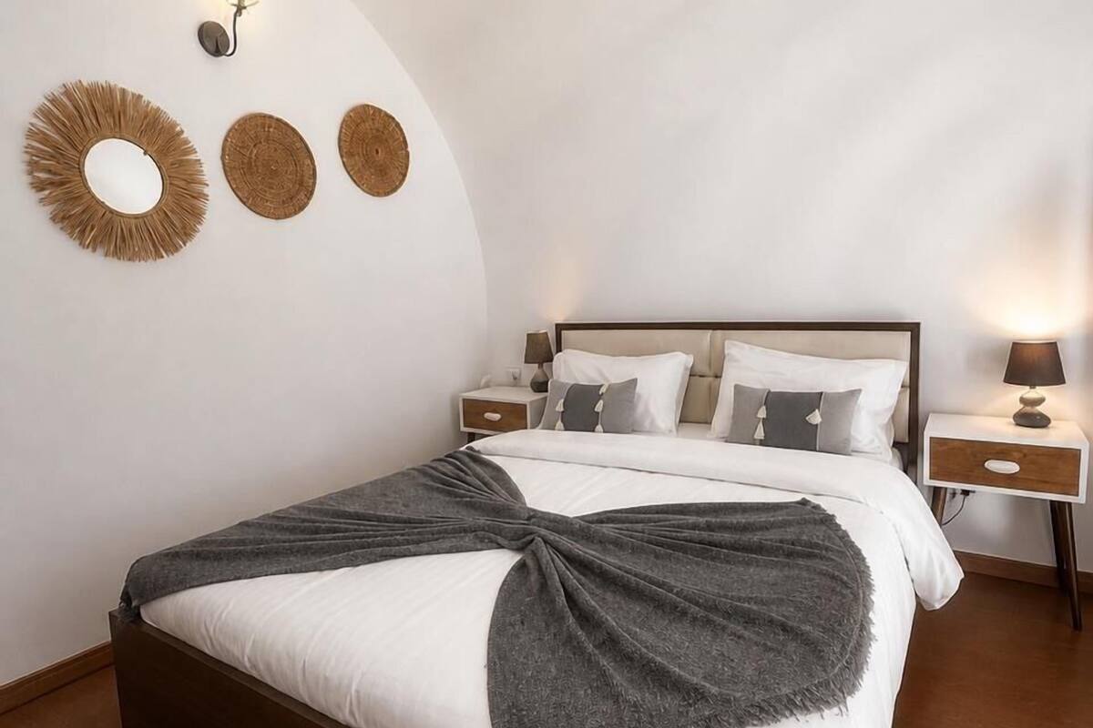 Un dormitorio con cama, mesitas de noche y decoración en la pared.