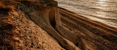 Un paisaje costero con una playa de arena y un acantilado.
