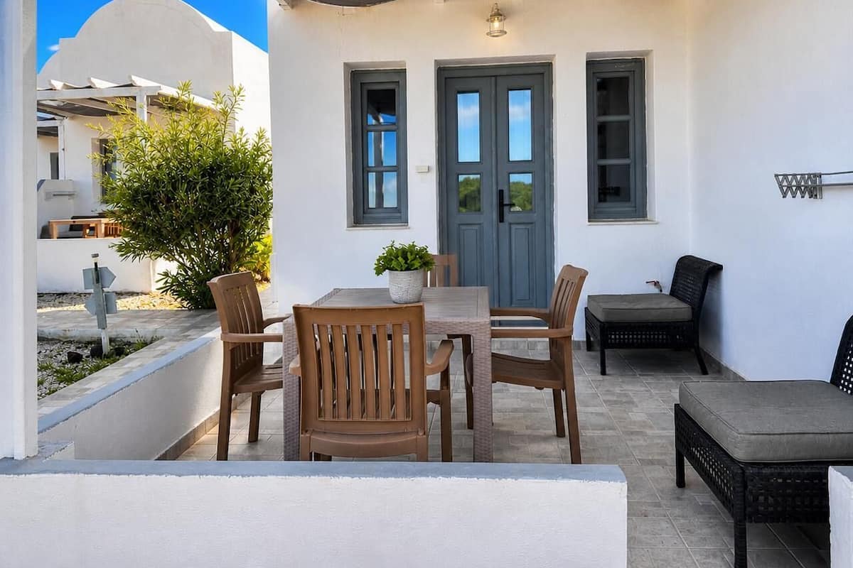 Un patio con una mesa, sillas, una puerta y una pequeña planta en maceta.
