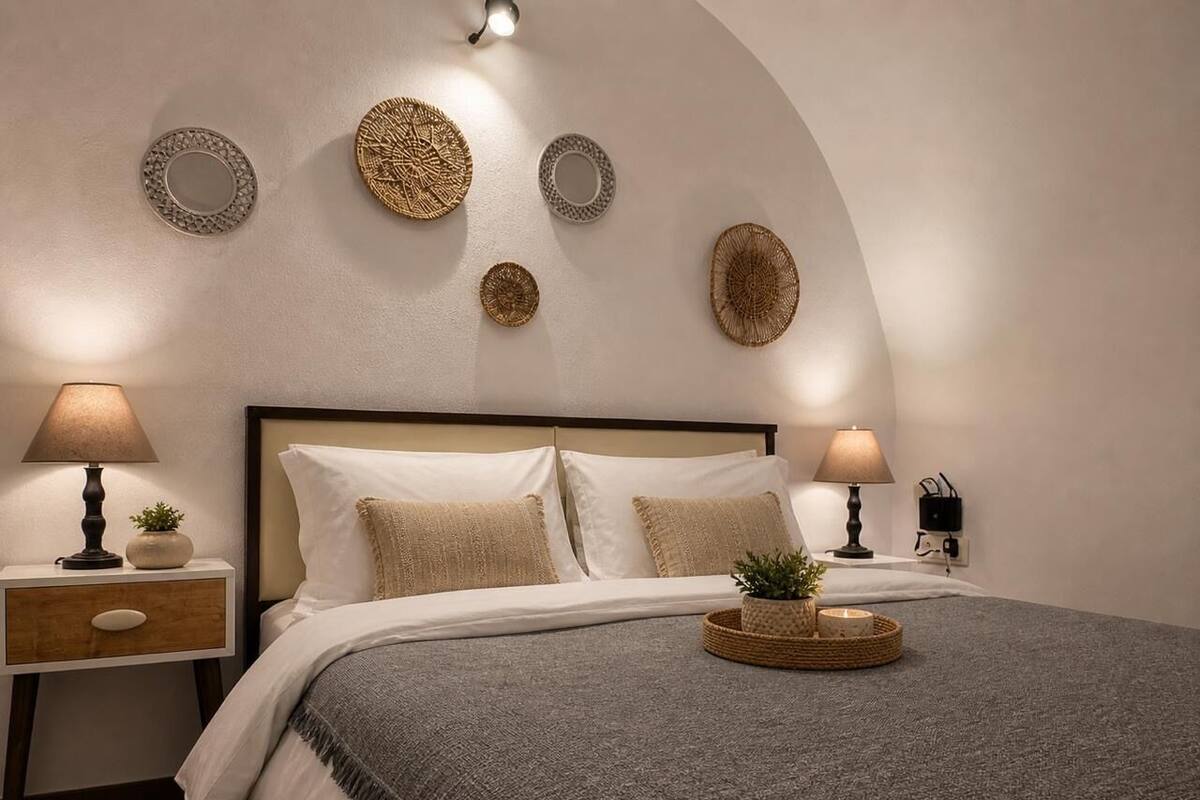 Un dormitorio con una cama, dos mesitas de noche, lámparas y adornos en la pared.