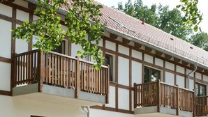 Un edificio de dos plantas con fachada de entramado tradicional, varios balcones con barandillas de madera y ventanas amplias.