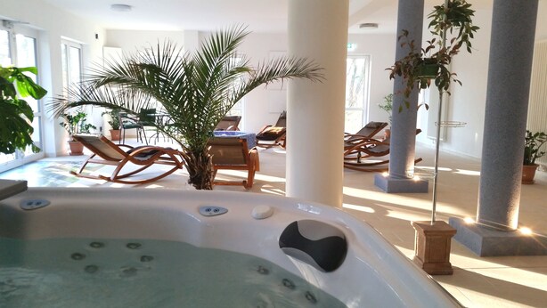 Un área de spa con jacuzzi, sillones reclinables y plantas en macetas.